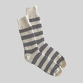 A pair of striped crew socks in cream and dark gray, shown floating against a solid light gray background.