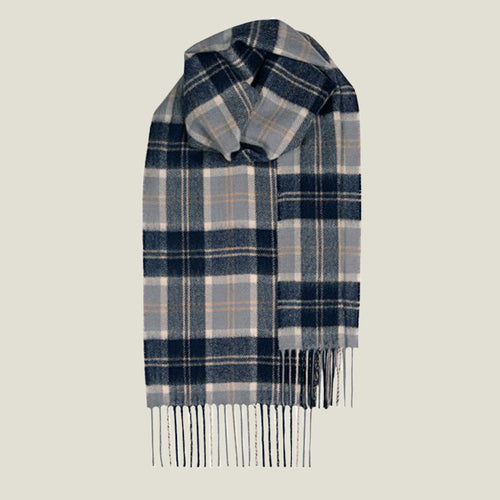 A classic plaid scarf in navy blue, light gray, and beige, styled with fringe at the bottom against a solid light gray background.