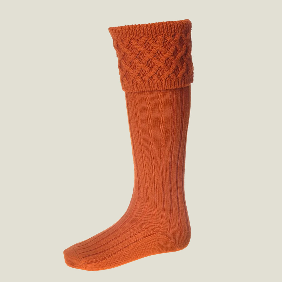 A single burnt-orange ribbed knit merino wool sock with a braided cable pattern cuff, shown on a light beige background.