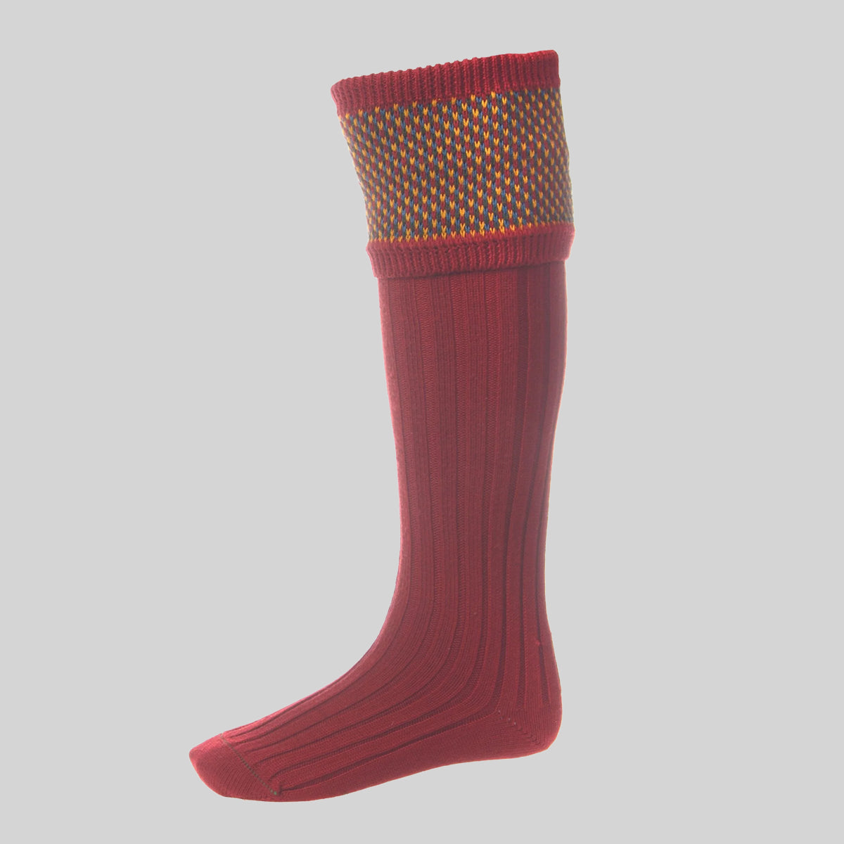 A vibrant brick red merino blend country style sock with a birdseye cuff edge in yellow and blue.