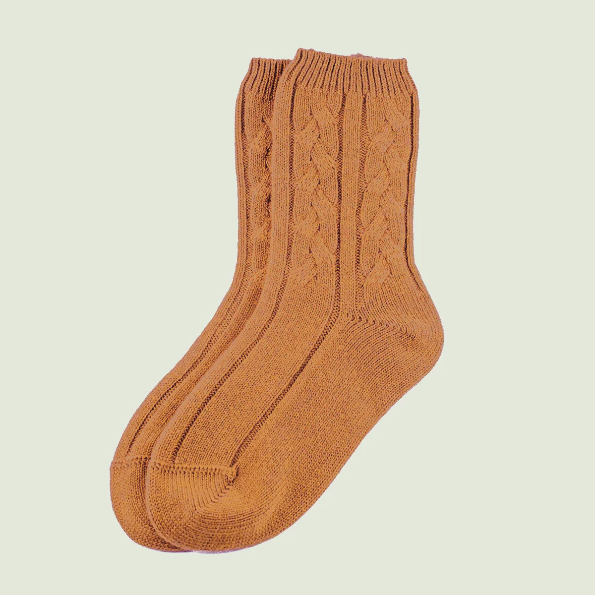 A pair of camel cable-knit crew socks shown against a solid light beige background.