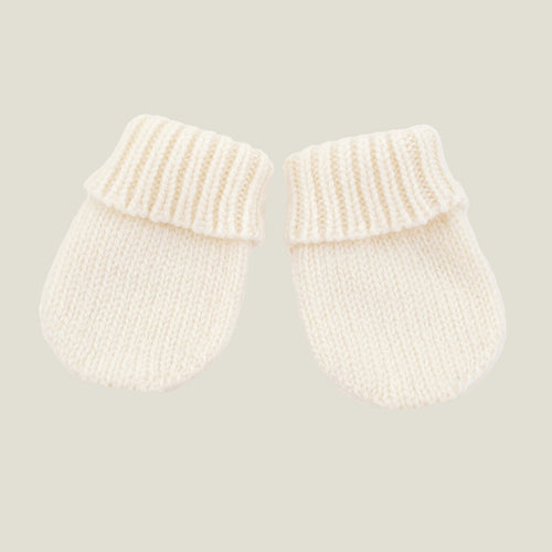 A pair of cream-colored cashmere knit baby mittens with ribbed cuffs, displayed on a solid light beige background.