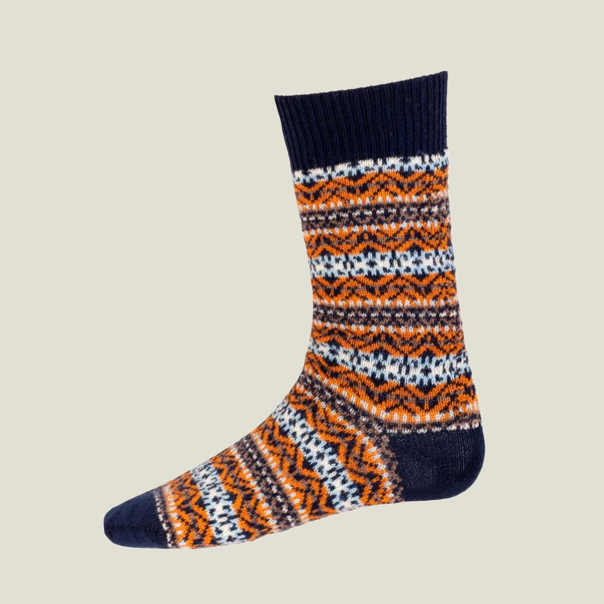 A single crew sock with a colorful Fair Isle pattern in orange, white, and dark navy blue, shown against a solid light beige background.