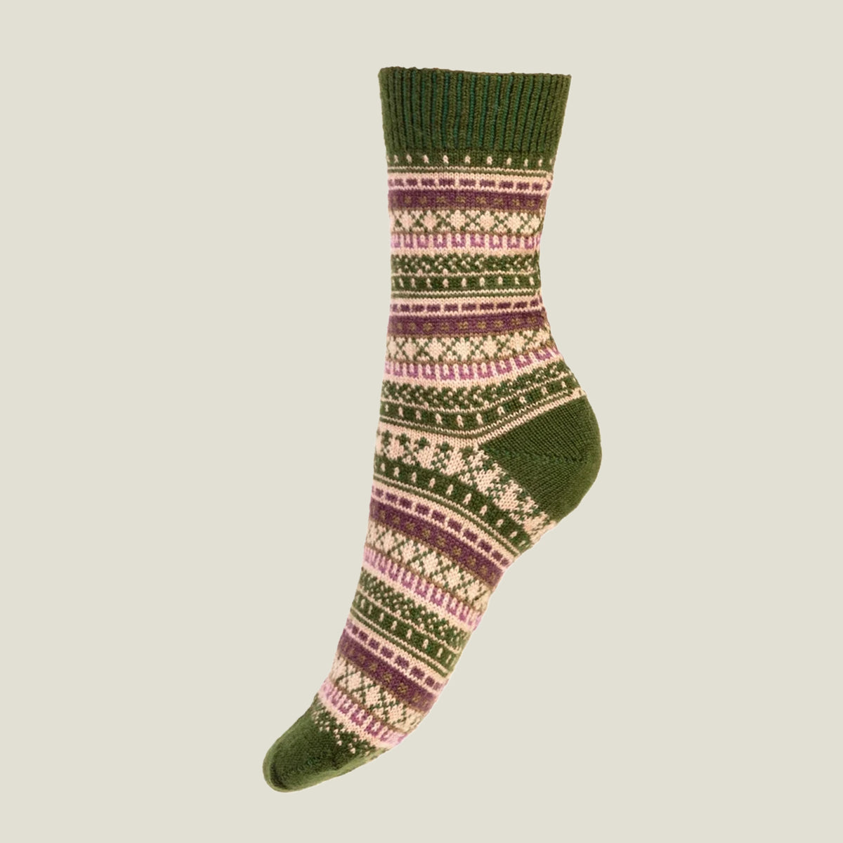 A single crew wool sock with a green ribbed cuff and heel, featuring a multicolor Fair Isle knit pattern in green, beige, and pink, set against a solid light gray background.