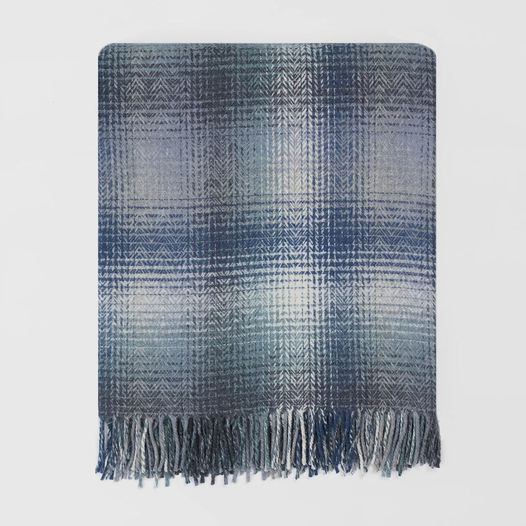A rectangular woven throw blanket with a blue and gray pattern and fringed edges, shown flat against a light gray background.