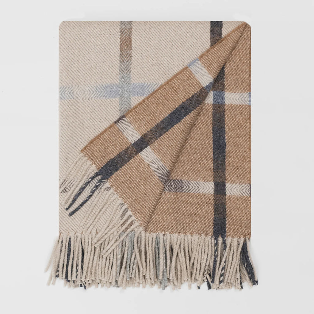A folded beige plaid lambswool blanket, cream on one side and brown on the other with overcheck design and fringed edge. Shown on a clean white background.