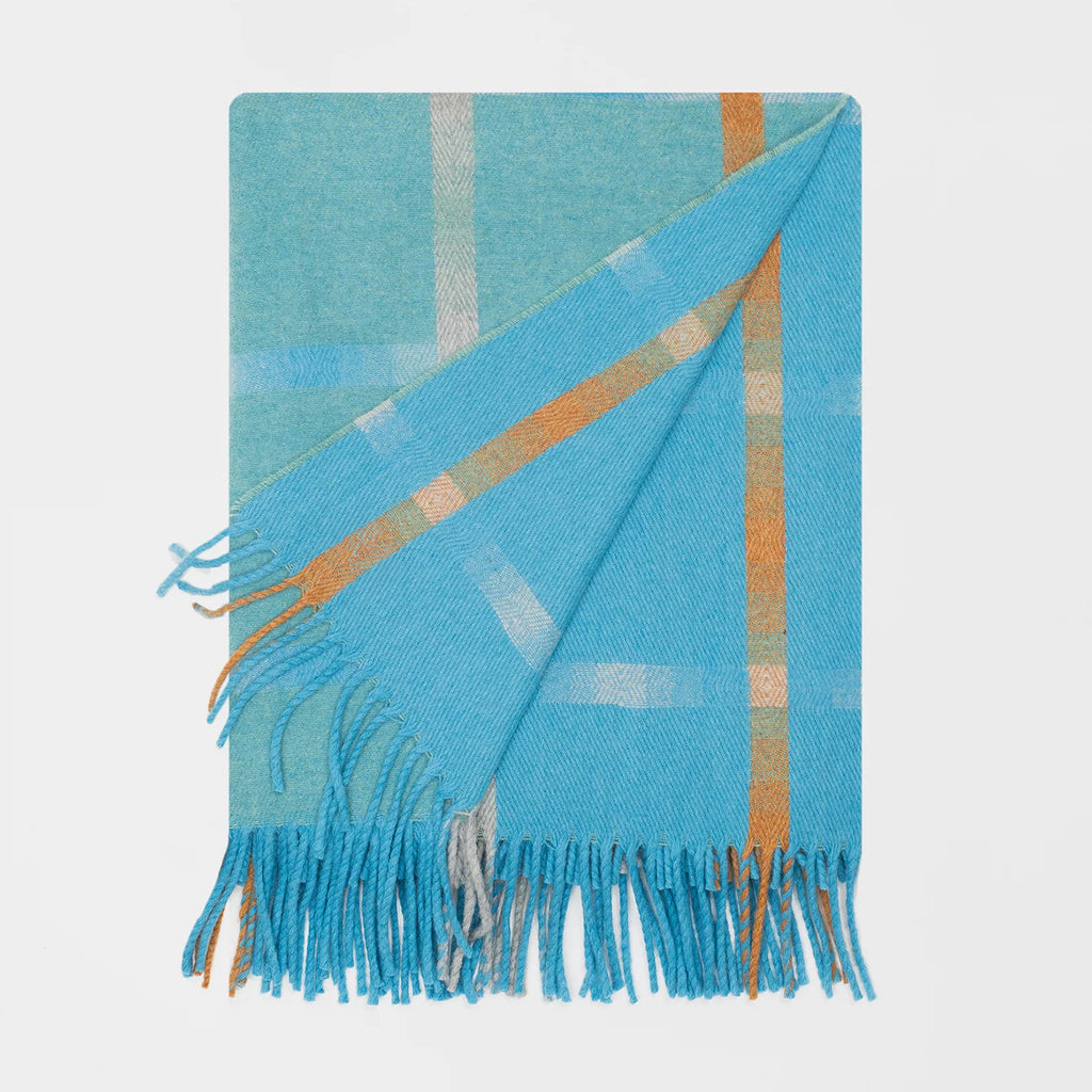 A folded plaid fringed throw blanket in bright turquoise / aqua blue with orange and white stripes, displayed on a clean white background. It shows both sides of this reversible blanket in slightly different shades of blue.