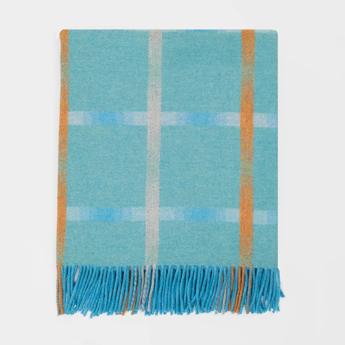 A folded plaid merino throw blanket with a light blue and turquoise base, featuring stripes in orange and subtle blue and cream. The bottom edge has matching fringed tassels.