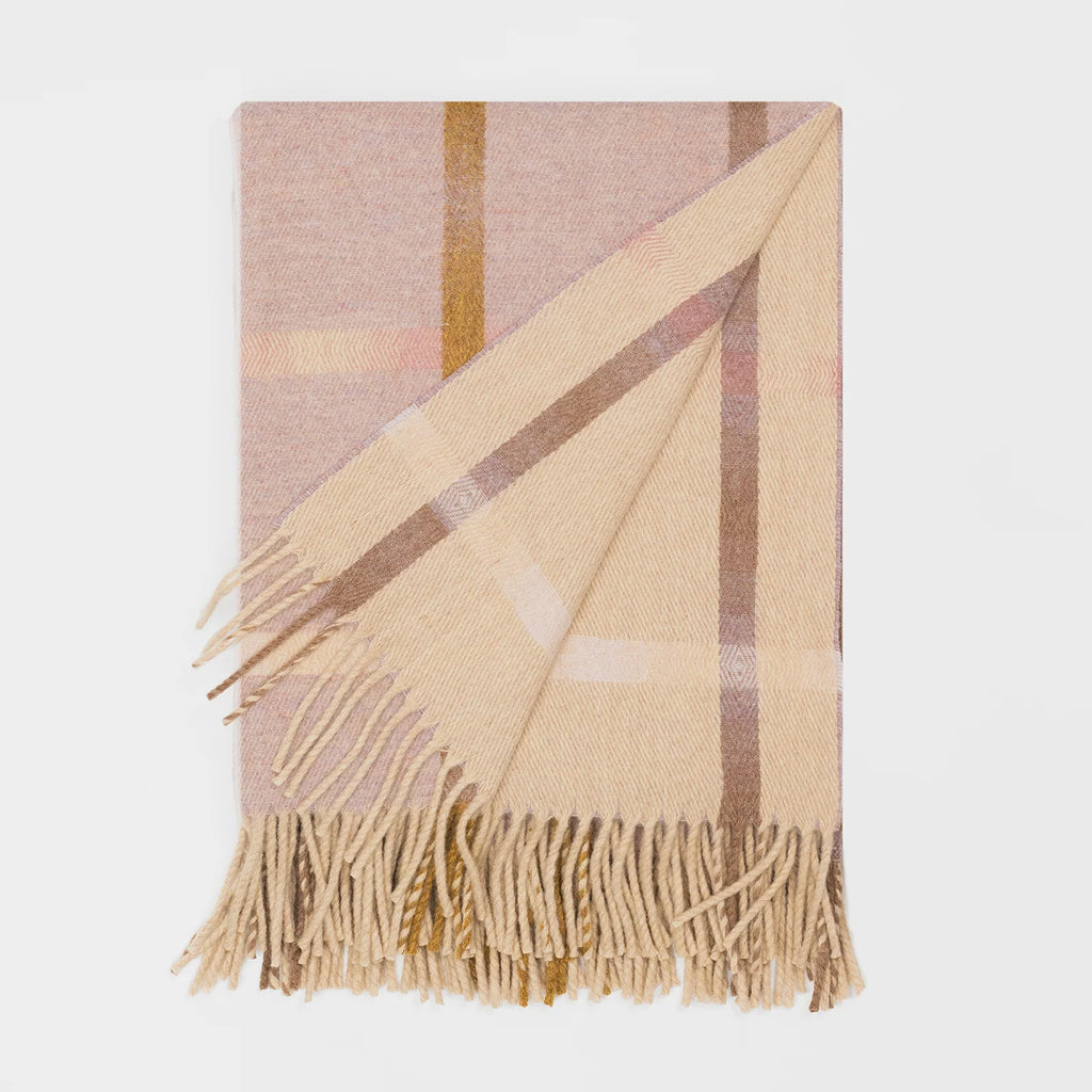 A folded plaid lambswool scarf with fringed ends, featuring a soft pink colour palette on one side and orange / beige on the other.