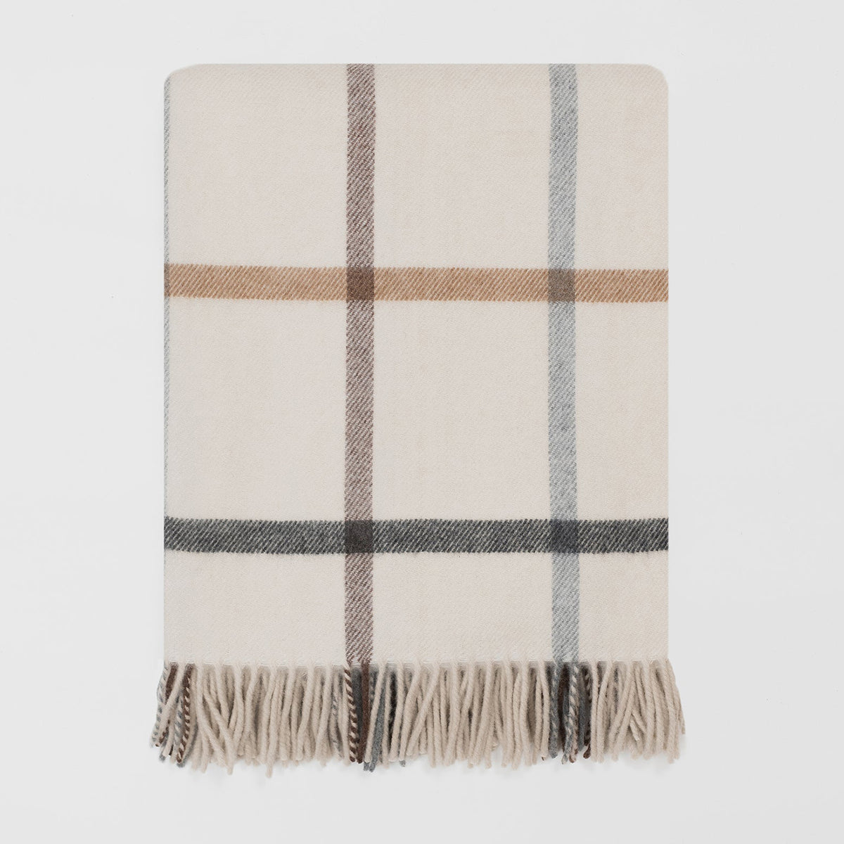A folded plaid throw blanket with cream, beige, brown, gray, and black stripes, finished with fringed edges, shown on a light gray background.