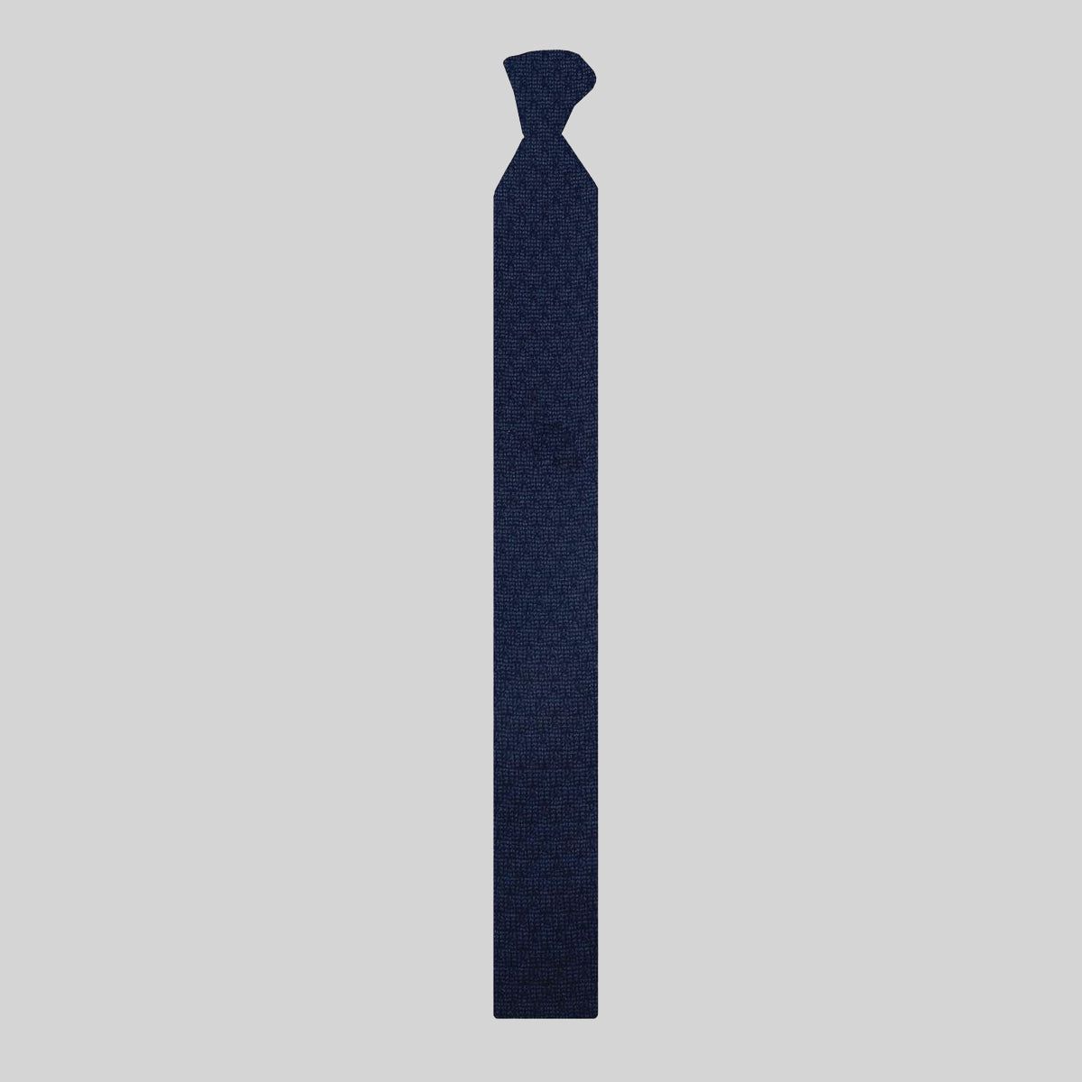 Blue patterned merino tie on a plain grey background.