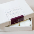 A boxed set of wax melts with the lid partially open, showing two round off-white wax melts inside. The label reads 'LOVE SCOTTISH' scent Black Pomegranate No.3