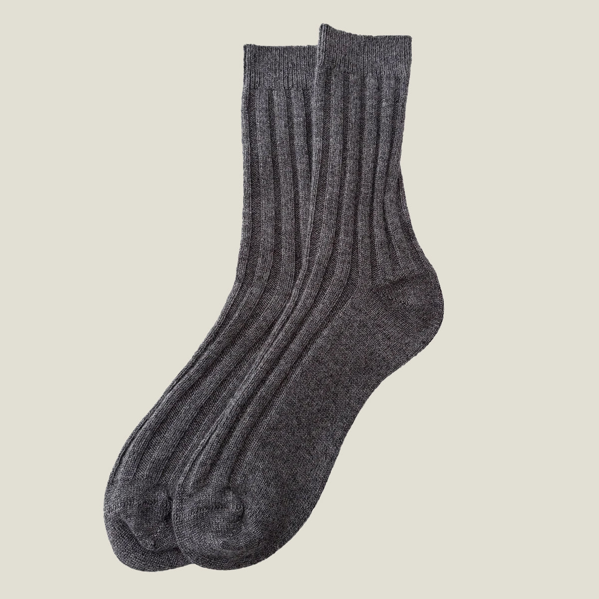 A pair of dark grey ribbed men's 100% cashmere socks displayed against a solid cream background.