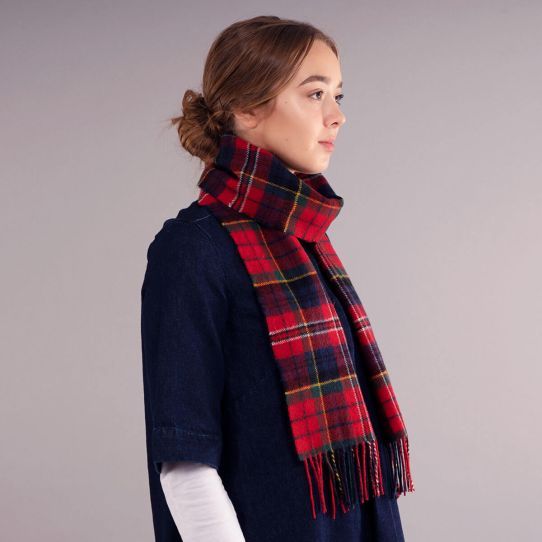 A side view of a woman wearing a red tartan scarf with hints of blue, green and yellow. Made from 100% lambswool.